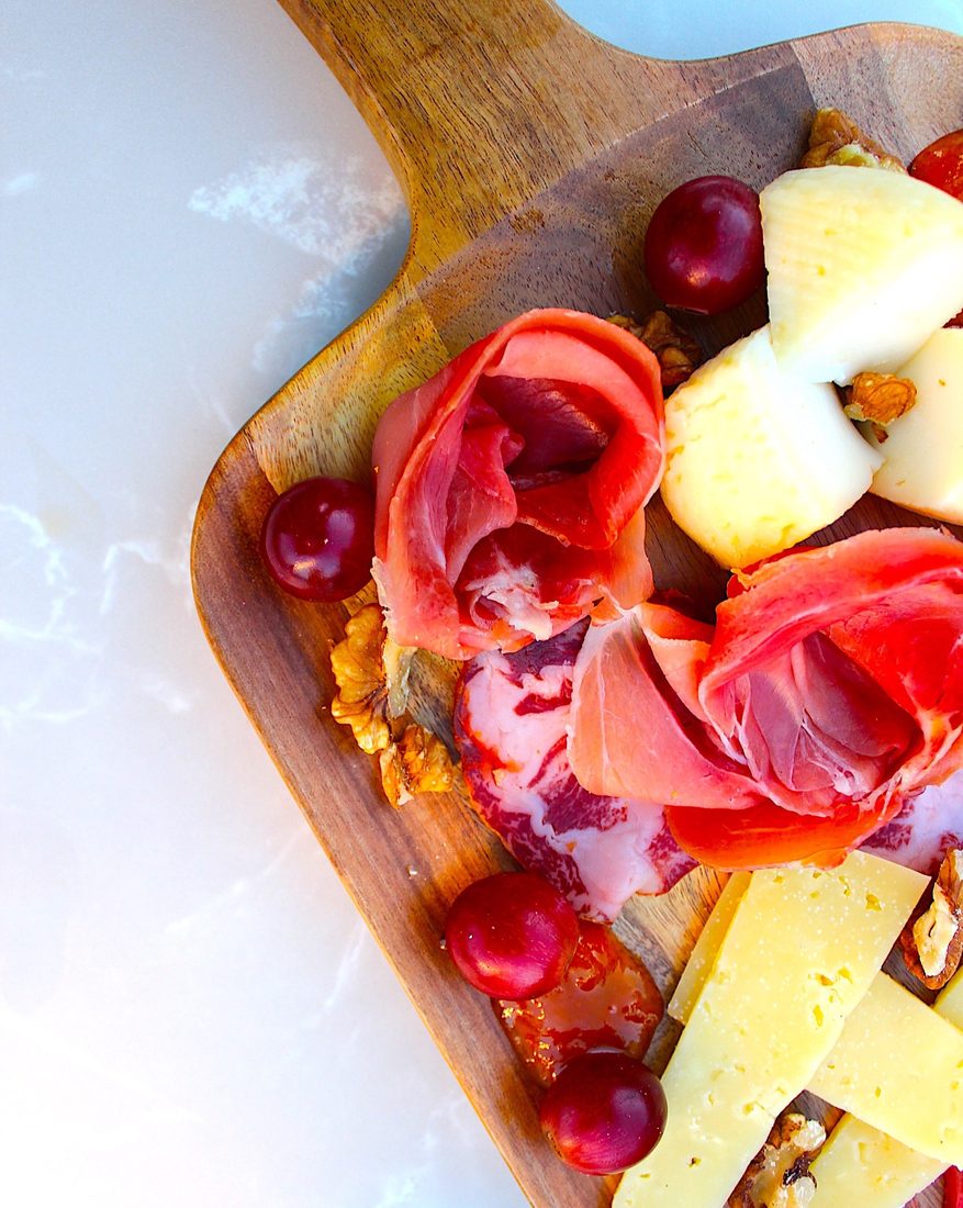 Tábua de charcutaria com queijos, enchidos, uvas e nozes